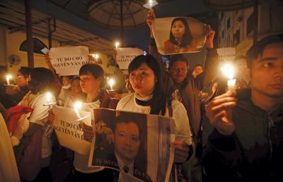 PRAYERS FOR FREEDOM. Protesters hold candles during a Mass at Thai Ha Redemptorist Church in Hanoi, Vietnam, on Dec. 27. Vu Minh Khanh, center, holds an image of her husband, Nguyen Van Dai, who was badly beaten by unknown attackers and arrested in December for anti-state “propaganda.”