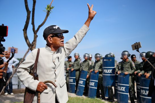 A man walks in front of riot police yesterday in Phnom Penh. Hong Menea
